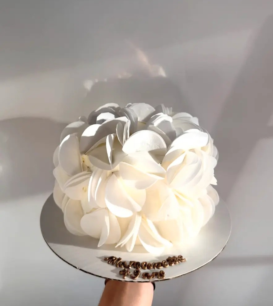Gâteau Dolceva ivoire couvert de volutes de crème, porté à la main