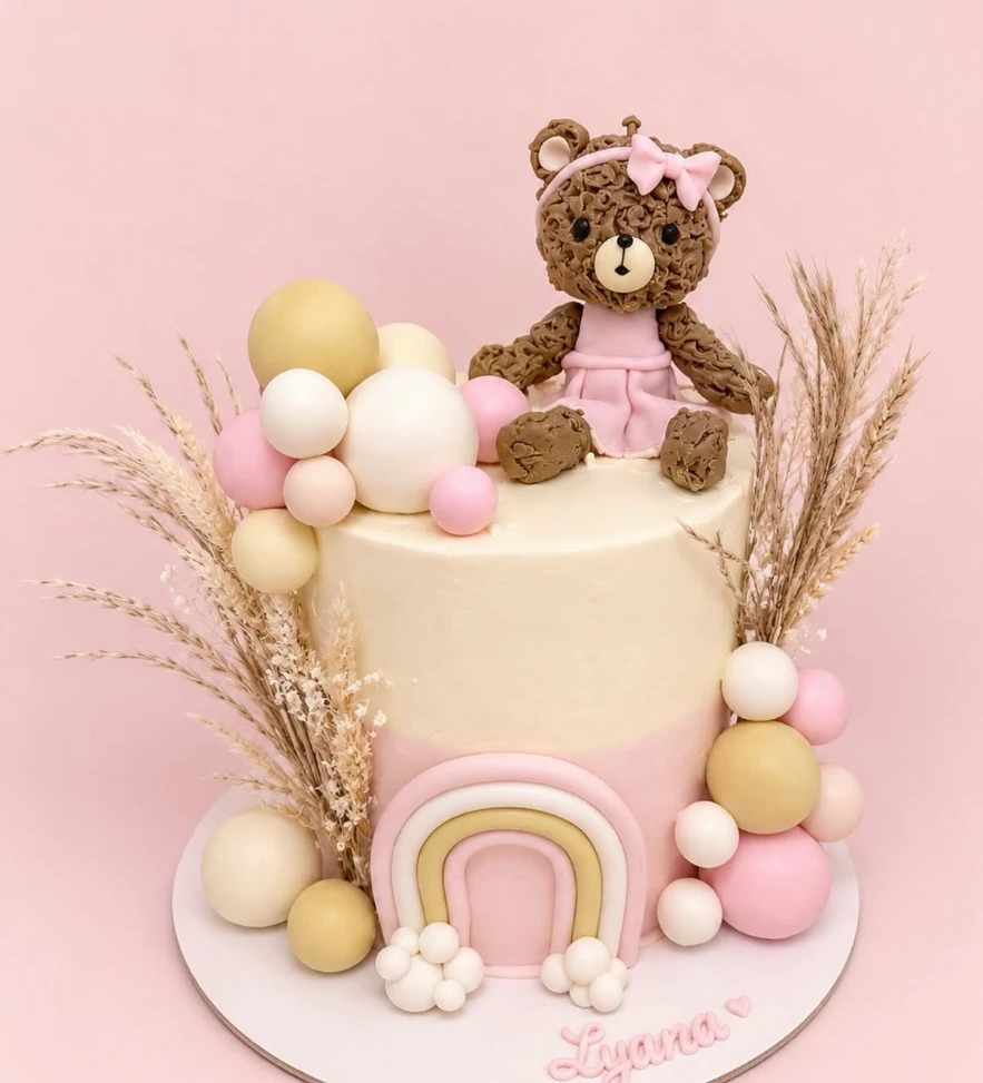 Gâteau rose poudré avec ourson modelé, ballons et arc-en-ciel pastel